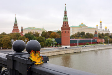 View of the Kremlin embankment and Moscow river at autumn, selective focus to fallen maple leaf on a bridge