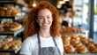 © Real People - A cheerful young European woman in an apron smiles warmly in a vibrant bakery, surrounded by fresh baked goods, showcasing a welcoming atmosphere and daily life in a food shop.