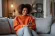 © gankevstock - Smiling woman relaxing on a comfortable couch using smartphone
