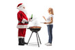 © Ljupco Smokovski - Santa claus toasting holding a beer and grilling meat on a bbq with a woman