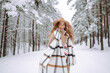 © maxbelchenko - Happy woman among snowy trees in winter forest, enjoying the first snow in hat and coat. Boho style. Active lifestyle and tourism.