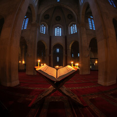 A holy scripture opened inside a beautifully lit place of worship, with candles surrounding the sacred space, creating a serene atmosphere