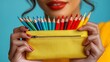 © anantachat - Bright colored pencil case alongside a row of sharpened pencils on a pastel colored surface Stock Photo with side copy space