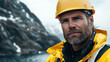 © kongkiat chairat - technician in yellow hard hat and waterproof jacket stands confidently against rugged coastal backdrop, showcasing resilience and determination in challenging conditions