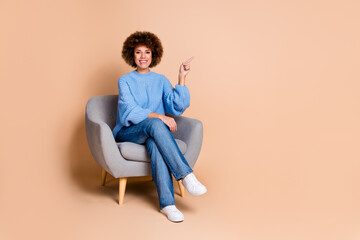 Canvas Print - Full size photo of cute girl dressed knit sweater jeans sit on armchair directing at promo empty space isolated on pastel color background