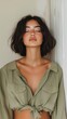 © Andrea Marongiu - Young woman exudes calm, leaning against a wall with eyes closed, showcasing natural beauty in a stylish green shirt