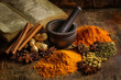 © alfi - Arrangement of medicinal spices with turmeric, ginger, cinnamon, cloves, and star anise beside mortar, pestle, and herbal book