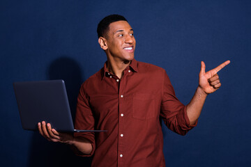 Poster - Photo of dreamy cool guy dressed brown shirt texting modern device pointing emtpy space isolated blue color background