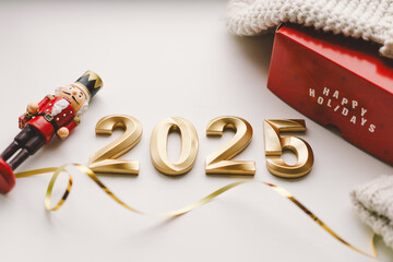 Happy new year 2025. A vibrant red gift box displaying the message of Happy Holidays sits beneath golden numbers marking the year 2025.