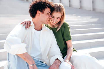 Canvas Print - Smiling beautiful woman and her handsome boyfriend. Couple in casual summer clothes. Happy cheerful family. Female and man having fun. They posing in the street in sunny day. Sit at stairs