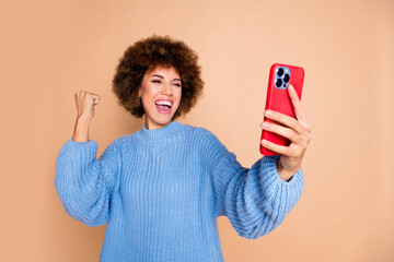 Canvas Print - Photo of ecstatic girl dressed blue knit sweater look at smartphone raising fist win lottery shout isolated on pastel color background