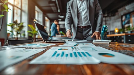 Poster - A businessman stands over a desk reviewing financial reports in a modern office.