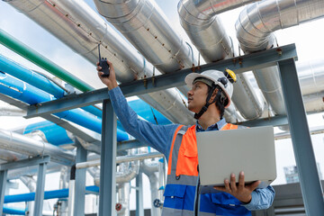 Man Industrial engineer with walkie talkie pointing work at rooftop construction. Male technician working checking HVAC system building factory. Installing large air conditioning system.