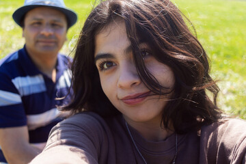 latina teenage girl smiles at camera and takes a selfie with her father