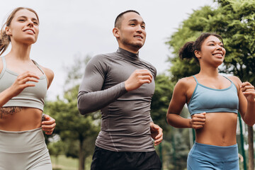 Diverse of smiling, happy runners wearing stylish sportwear running, training together on the street