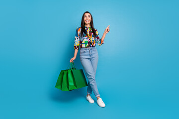 Canvas Print - Full length photo of overjoyed woman wear shirt hold shopping bags look directing at sale empty space isolated on blue color background