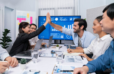 Analyst team leader celebrate and high five together with his colleague after successful data analysis meeting using FIntech software power with business intelligence or BI dashboard. Prudent