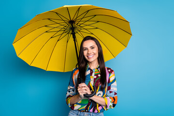 Wall Mural - Portrait of good mood lovely girl with straight hair dressed print blouse hold umbrella in rainy weather isolated on blue color background