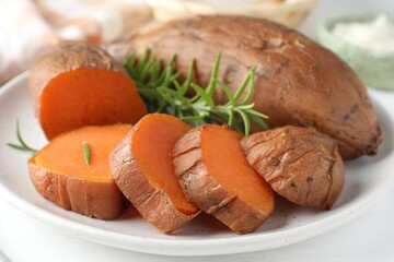 Tasty cooked sweet potatoes and rosemary on table, closeup