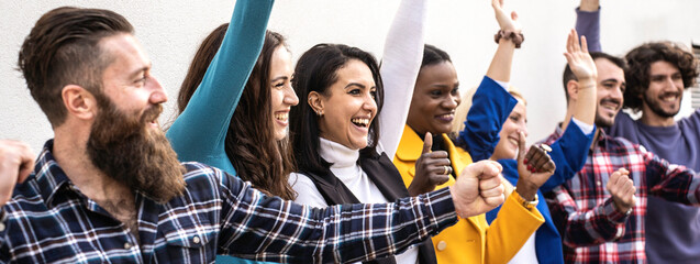 Group of diverse young adults celebrating success together with raised fists and smiles in a vibrant outdoor setting. A joyful moment of collective achievement.