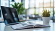 © Bonsales - Modern home office setup featuring a sleek laptop, an open book, and a decorative plant on a bright white table