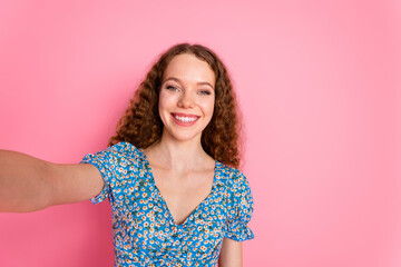 Wall Mural - Smiling woman taking a cheerful selfie against pink background