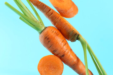 Wall Mural - Whole and cut fresh carrots on light blue background, closeup