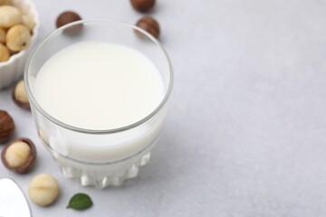 Wall Mural - Glass of macadamia milk and nuts on white table, closeup. Space for text