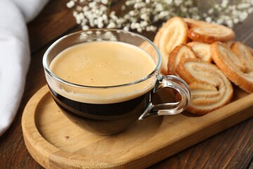 Wall Mural - Tasty french palmier cookies and coffee on wooden table, closeup