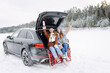 © maxbelchenko - Happy friends in winter forest in the car. Two happy girls sit in the trunk of a car talking and laughing.