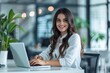 © Isuru - Young businesswoman smiling  typing on laptop at modern workstation.