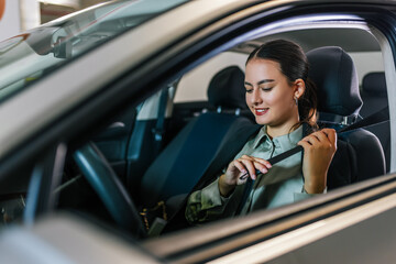 Young businesswoman putting a seatbelt on. Ready to drive off from his parking spot in an underground garage.