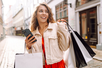 Wall Mural - Happy Woman use mobile phone and hold shopping bag. Black Friday. Sale. Online shopping.