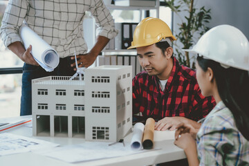 Wall Mural - team of architects are studying blueprints and working on a model of a building in their office