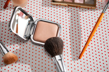 Makeup essentials including compact powder and brush on a polka dot background for beauty and fashion