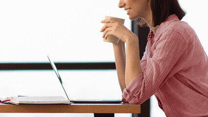 Poster - Morning Coffee. Cropped photo of happy student holding white coffee mug, watching video on laptop, empty space