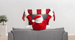 © Ljupco Smokovski - Santa Claus cheering with a scarf and sitting on a couch in front of tv