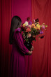 © Milou Dirks - woman with bouquet of flowers in artistic studio style with red dress and curtains