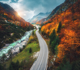 Wall Mural - aerial view of curvy road and orange forest in mountains in fall