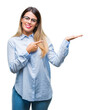 © Krakenimages.com - Young beautiful business woman wearing glasses over isolated background amazed and smiling to the camera while presenting with hand and pointing with finger.