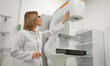 © My Ocean studio - Female doctor in a white coat operates a mammography machine in a modern medical facility, adjusting the settings for a breast cancer screening procedure, emphasizing advanced healthcare technology.