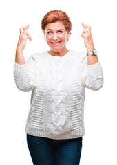 Wall Mural - Atrractive senior caucasian redhead woman wearing winter sweater over isolated background smiling crossing fingers with hope and eyes closed. Luck and superstitious concept.