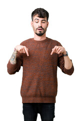 Wall Mural - Young handsome man wearing winter sweater over isolated background Pointing down with fingers showing advertisement, surprised face and open mouth