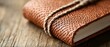 © N0X - A close-up of a textured leather-bound notebook tied with twine, resting on a rustic wooden surface.