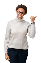 Young beautiful african american woman wearing glasses over isolated background Pointing to the back behind with hand and thumbs up, smiling confident