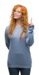 © Krakenimages.com - Young redhead woman wearing glasses surprised with an idea or question pointing finger with happy face, number one