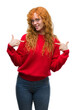 © Krakenimages.com - Young redhead woman wearing red sweater looking confident with smile on face, pointing oneself with fingers proud and happy.