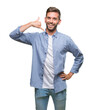 © Krakenimages.com - Young handsome man wearing white t-shirt over isolated background smiling doing phone gesture with hand and fingers like talking on the telephone. Communicating concepts.