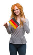 © Krakenimages.com - Young redhead woman holding flag of Germany happy with big smile doing ok sign, thumb up with fingers, excellent sign