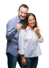 Middle age hispanic business couple over isolated background doing happy thumbs up gesture with hand. Approving expression looking at the camera with showing success.